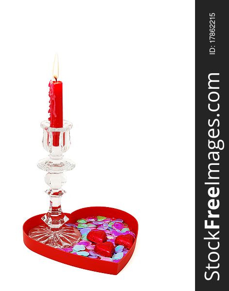 Red candle in glass candlestick on heart shaped tray with candies and sparkles. Red candle in glass candlestick on heart shaped tray with candies and sparkles