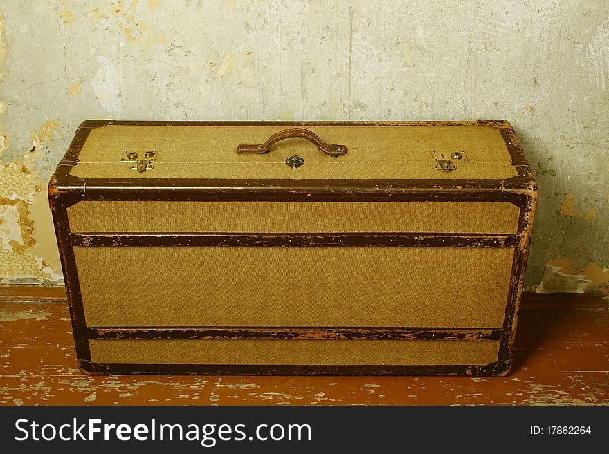 Old-fashioned suitcase standing on the old wooden floor