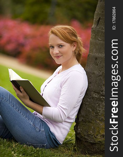 Young woman sitting outside reading. Young woman sitting outside reading