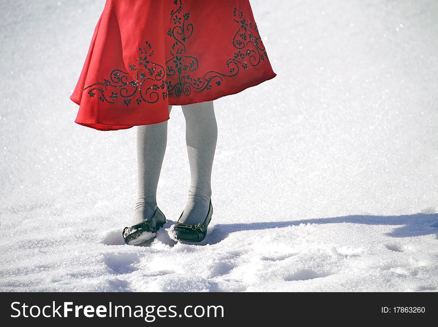 Young girl standing in the snow in a bright red dress. Young girl standing in the snow in a bright red dress.