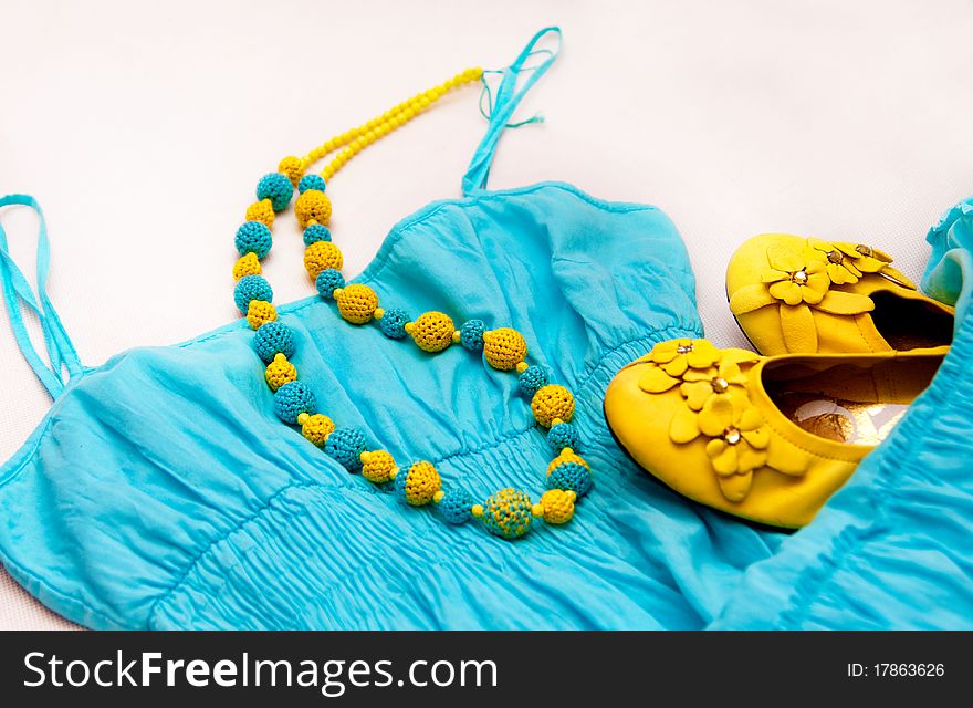 Crocheted yellow blue beads on a blue dress and yellow shoes as a background. Crocheted yellow blue beads on a blue dress and yellow shoes as a background