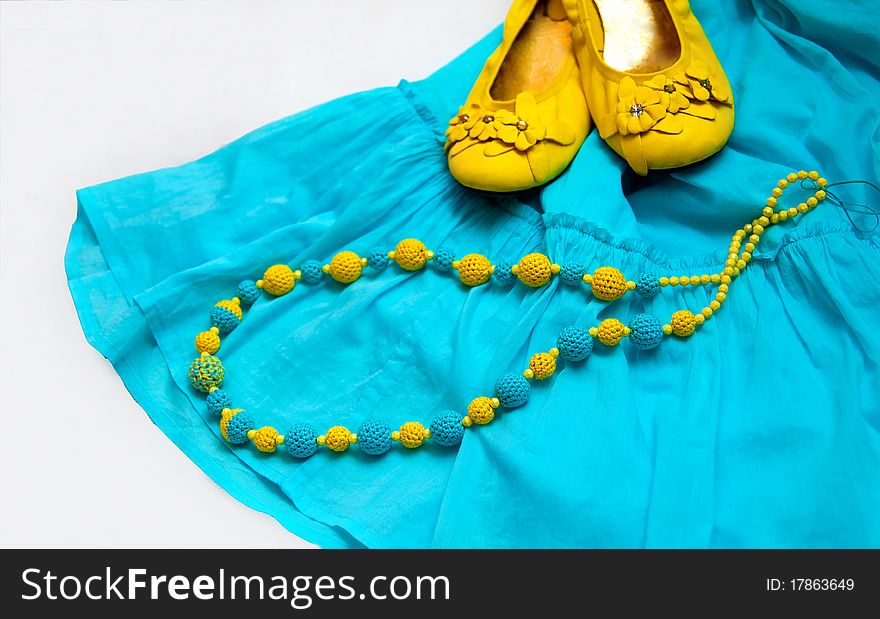 Crocheted yellow blue beads on blue dress and yellow shoes as a background. Crocheted yellow blue beads on blue dress and yellow shoes as a background