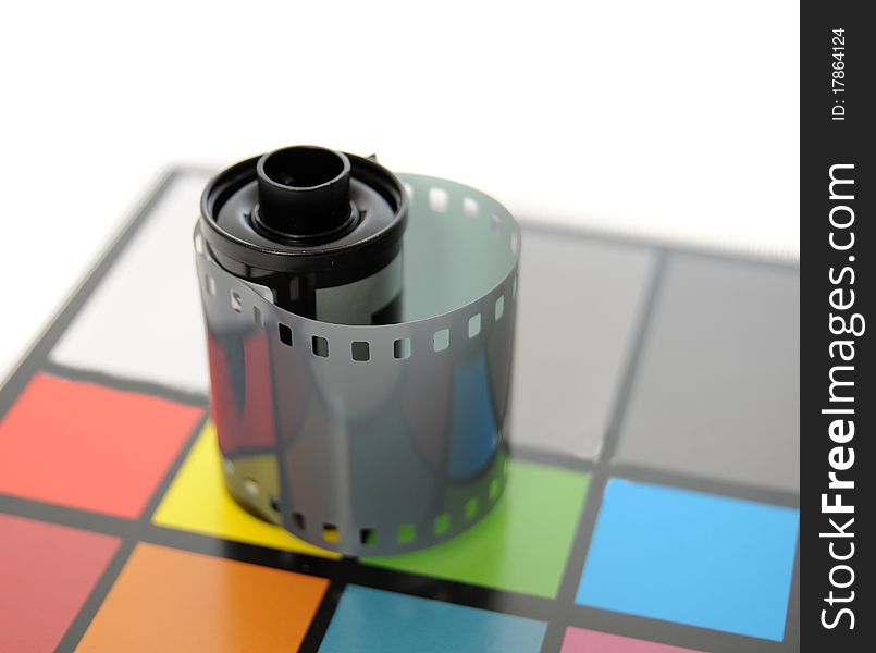 Roll of 35mm Film on top of color calibrated card of squares. Roll of 35mm Film on top of color calibrated card of squares.