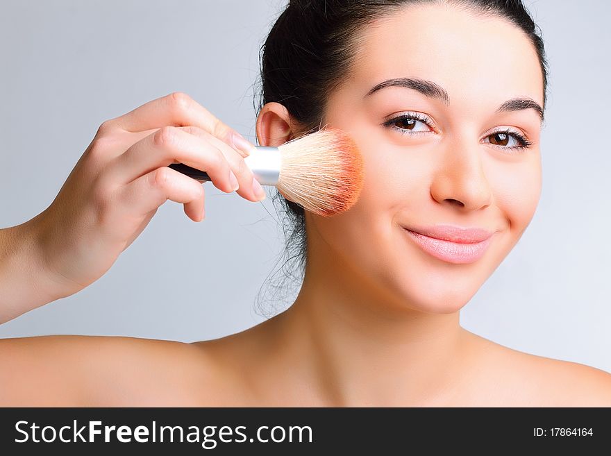 Beautiful woman applying make-up with brush