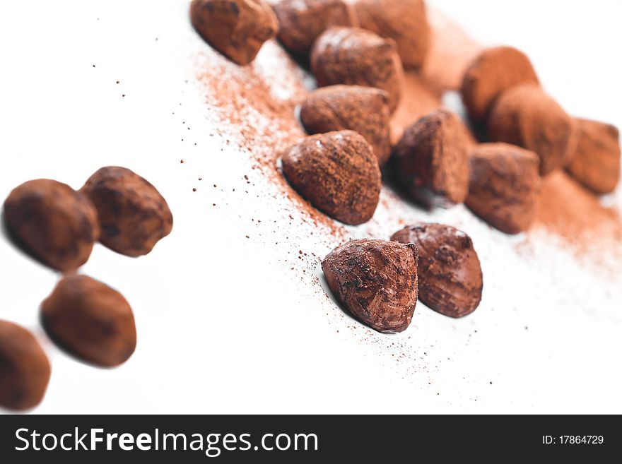 Chocolate truffles and cocoa powder on a white background