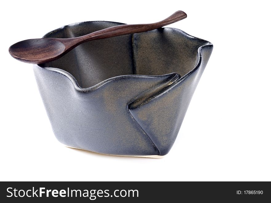 A glazed ceramic bowl with folded patterns, and a matching color wooden spoon. A glazed ceramic bowl with folded patterns, and a matching color wooden spoon.