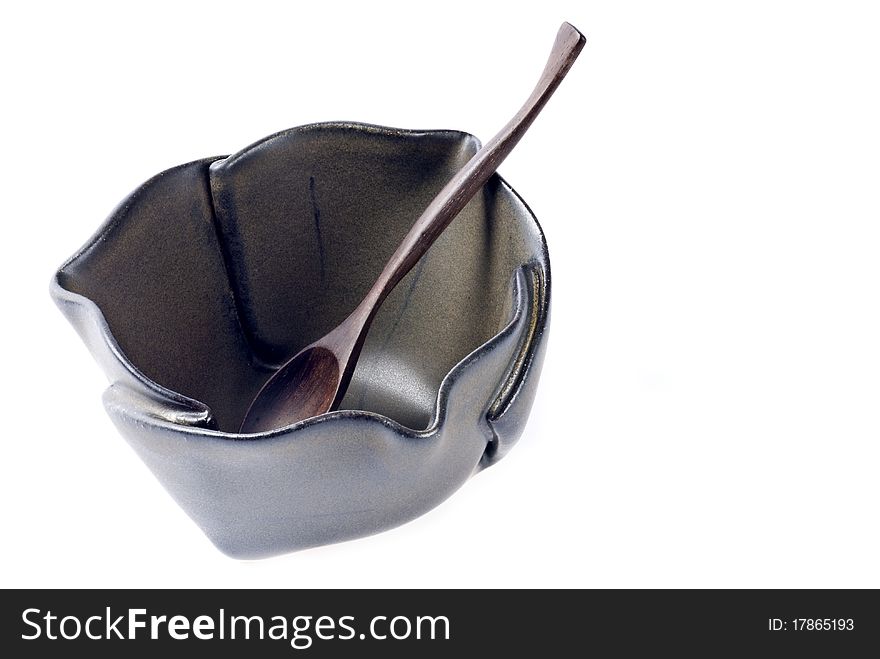 A glazed ceramic bowl with folded patterns, and a matching color wooden spoon. A glazed ceramic bowl with folded patterns, and a matching color wooden spoon.