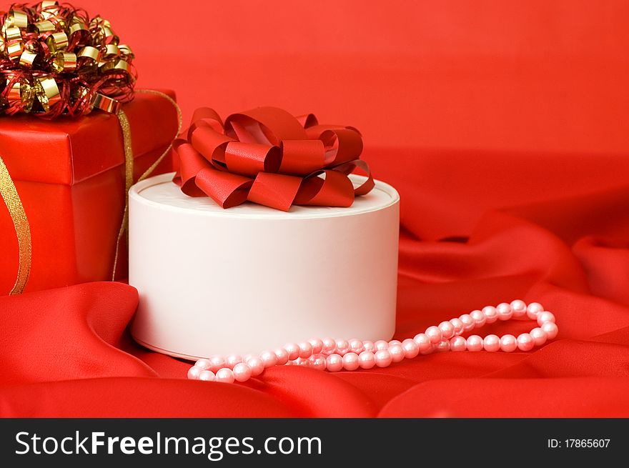 Box with a gift on a red fabric still life