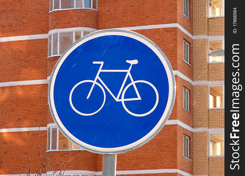 The sign of a cycle track on the background of a brick high-rises