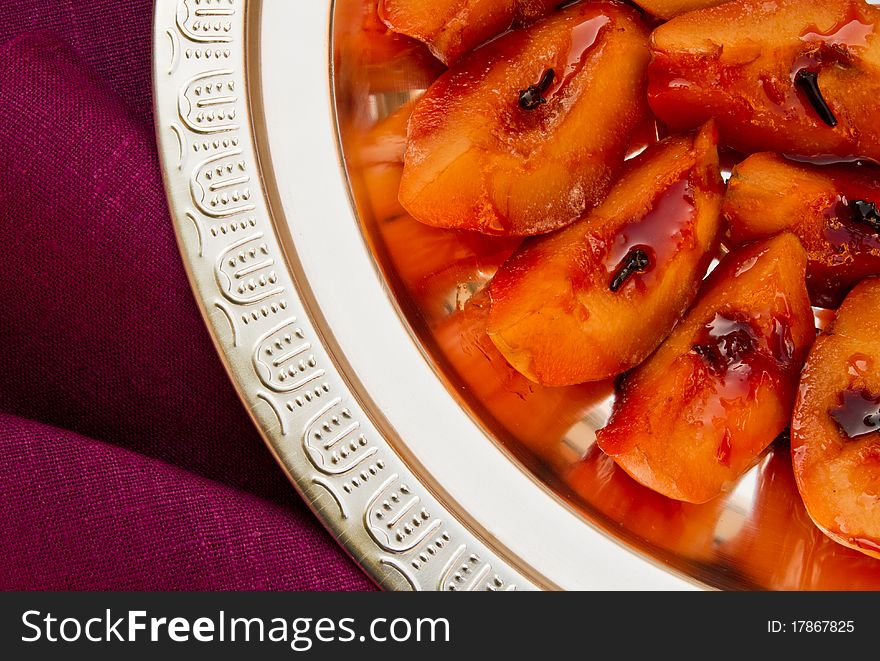 Silver plate with poached quince on bright violet table-cloth