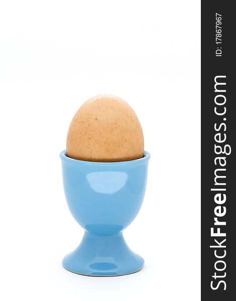 Egg in blue egg cup on white background. Egg in blue egg cup on white background