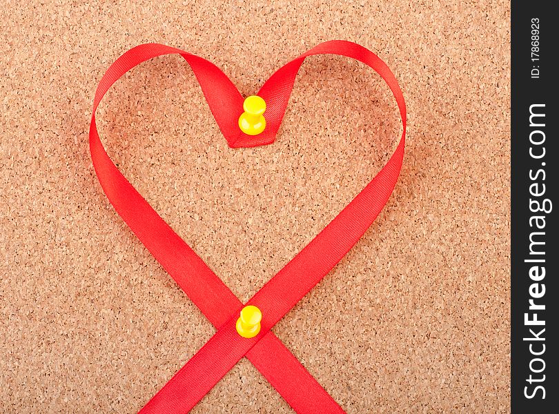 Red heart shaped ribbon pinned to cork board