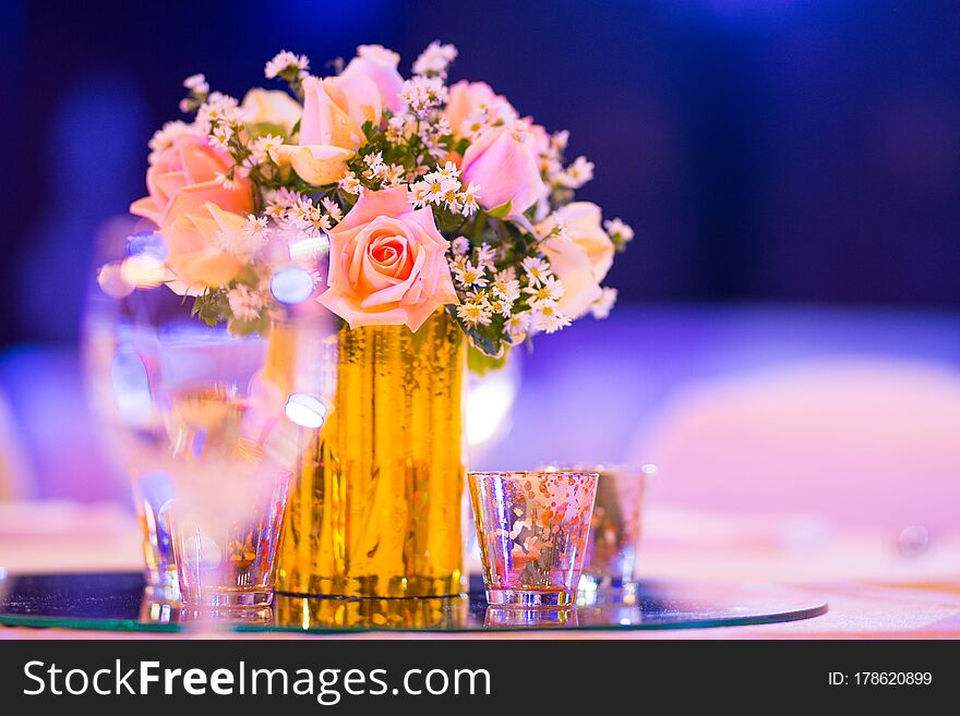 Rose florist in glass vase decoration on dinner table with silverware and candle Indian wedding setup indoor with decorative lights and beautiful bokeh. Rose florist in glass vase decoration on dinner table with silverware and candle Indian wedding setup indoor with decorative lights and beautiful bokeh.