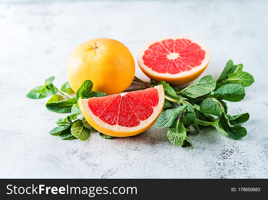 Red grapefruit with slaces and mint leaves on a light background. tinting. selective focus