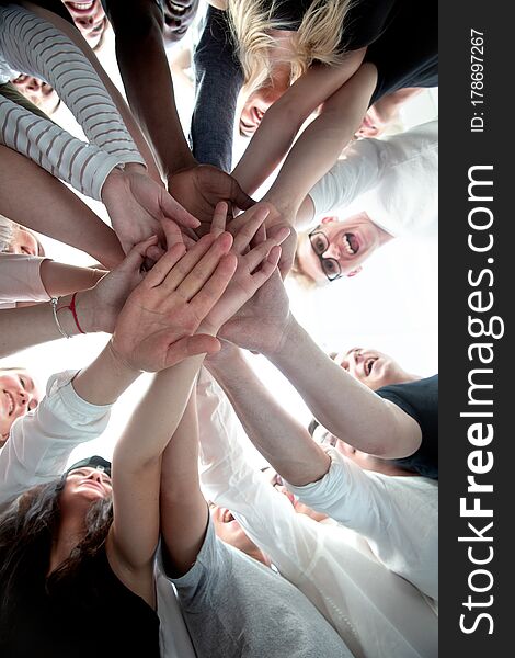 Bottom view . group of young people joining their palms together . the concept of team building