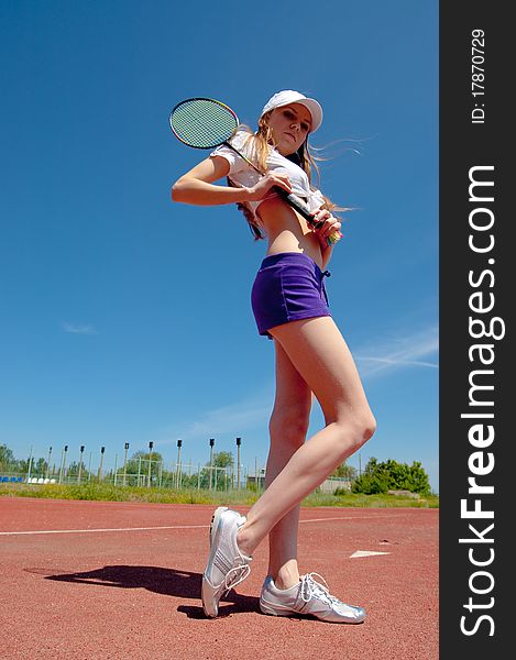 Beautiful girl on a tennis court on a background dark blue sky. Beautiful girl on a tennis court on a background dark blue sky