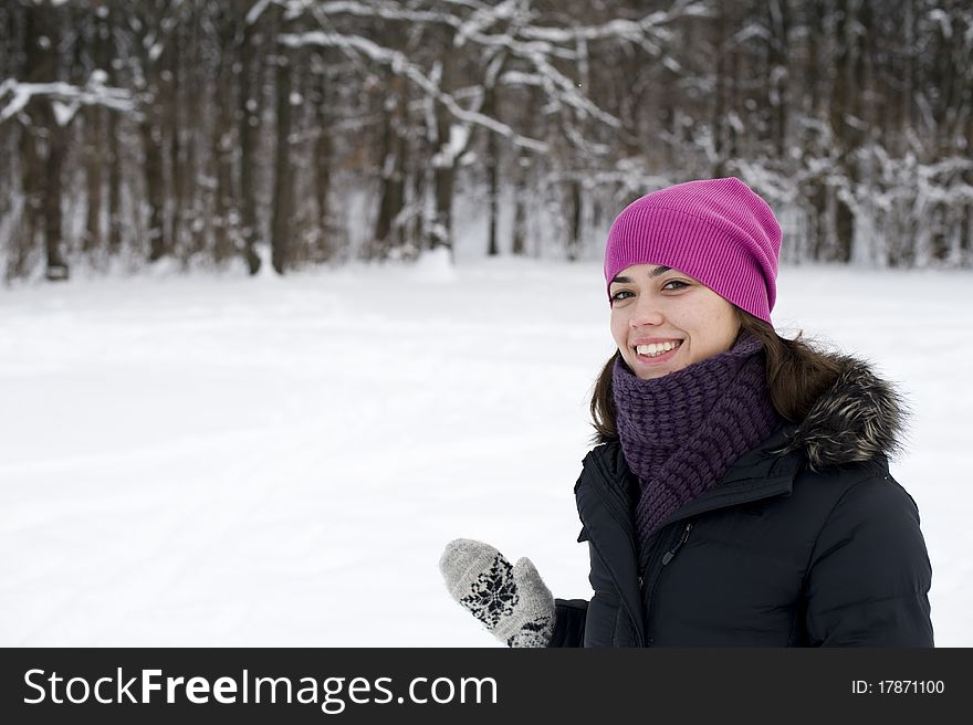 The young happy woman the brunette smiles against winter wood