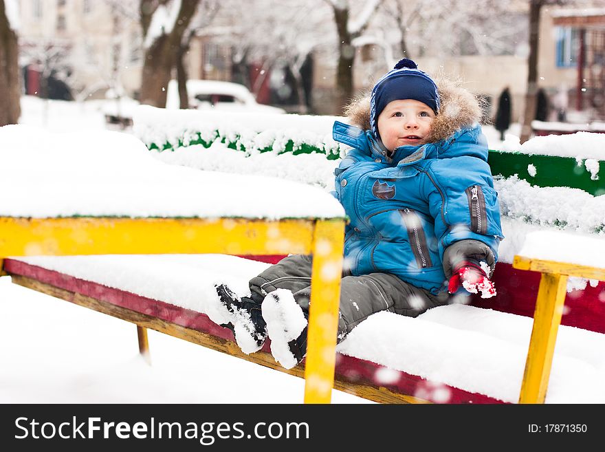 Cute boy sitting in snow outdoor