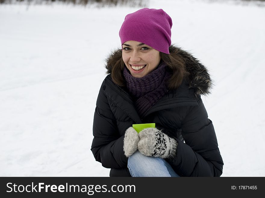 The Young Happy Woman Sits On Snow With Hands A Cu