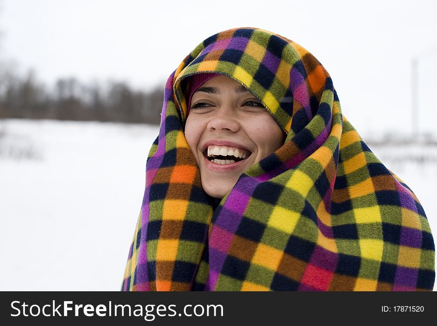 The young happy woman laughs having taken cover a color checkered plaid