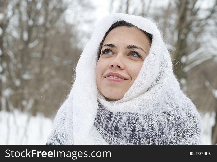 The young happy woman in a white knitted scarf laughs and smiles