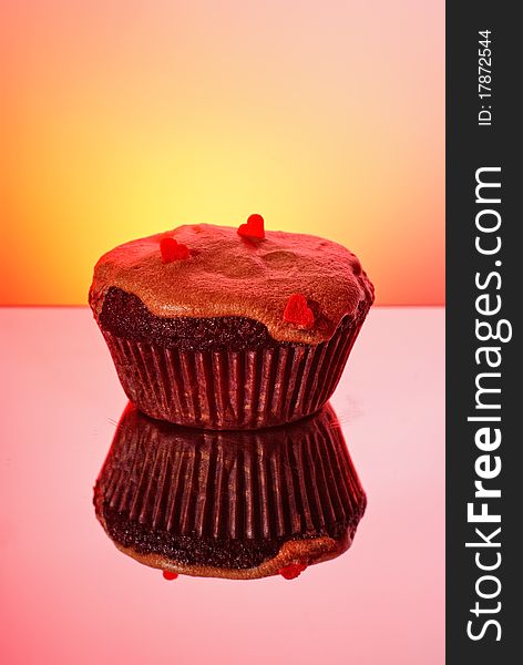 Sweet cupcake for St. Valentine day with hearts on it and reflection on red background. Sweet cupcake for St. Valentine day with hearts on it and reflection on red background