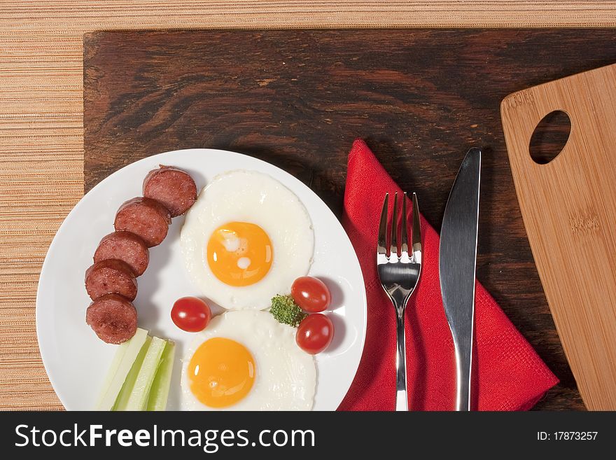 Fried eggs with fried sausage and vegetables.