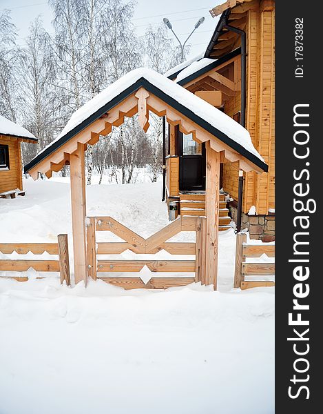 Front door to the cottage, winter chalet or a suburban house covered with snow, residential structure, building exterior, non-urban scene, residential districtstained. Front door to the cottage, winter chalet or a suburban house covered with snow, residential structure, building exterior, non-urban scene, residential districtstained