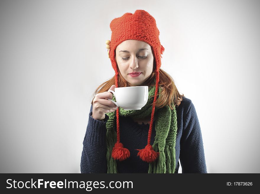 Young woman in winter clothes holding a bowl of hot drink