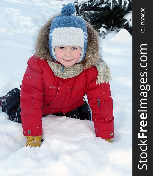 The boy lay on the snow in the bright winter clothes. The boy lay on the snow in the bright winter clothes