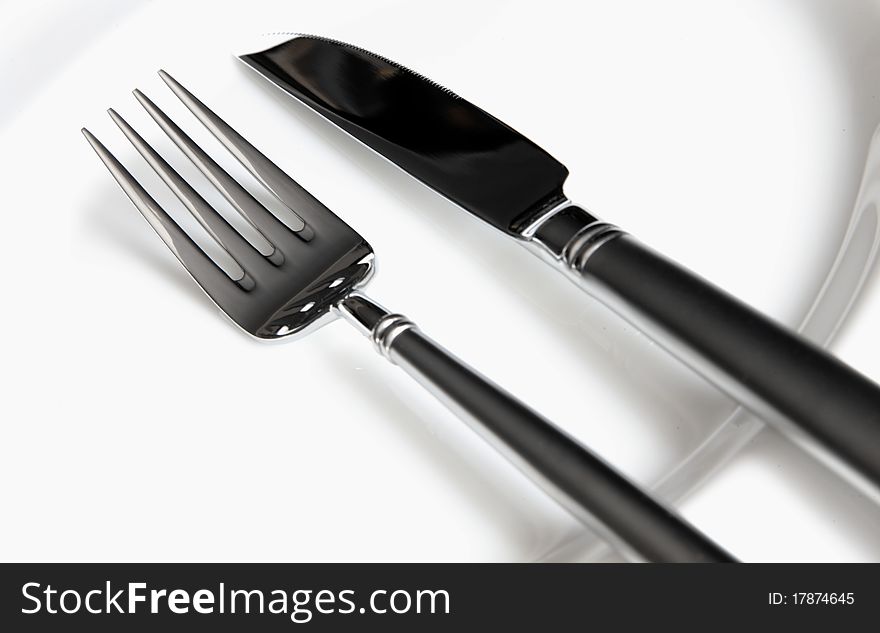 Silverware, knife and fork on a white plate