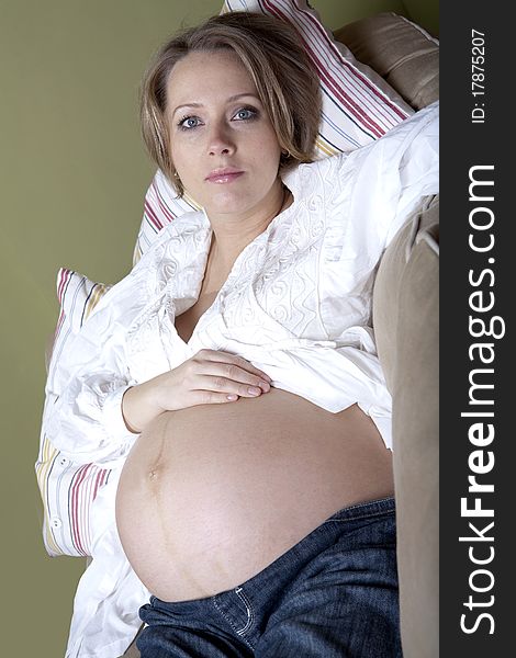 Beautiful pregnant woman relaxing on couch at home`
