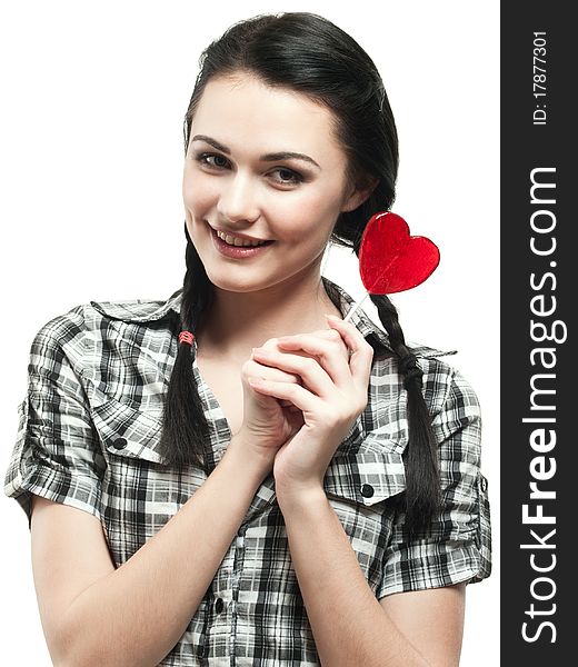 Young smiling girl with red heart lolipop isolated on white