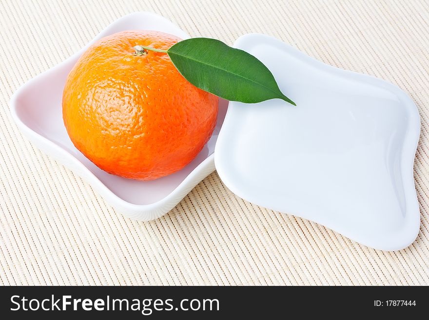 Tangerine on white plate with cover