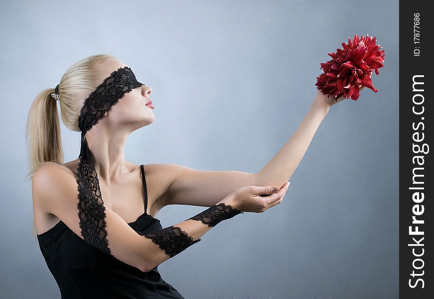 Emotional blonde girl with closed eyes and red flower at hand. Emotional blonde girl with closed eyes and red flower at hand