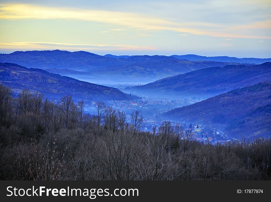 Fog over large valley village under sunny winter day