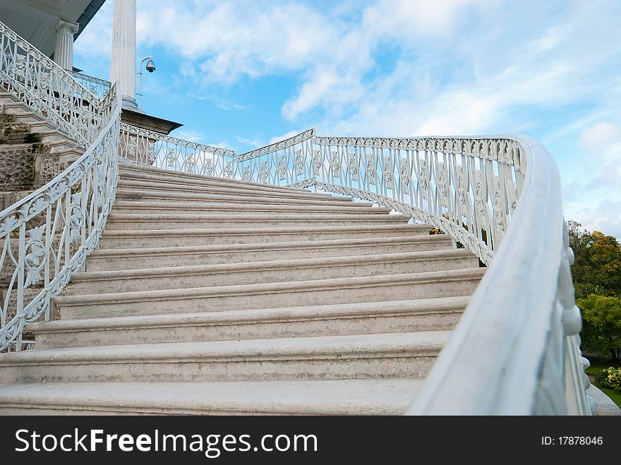 Marble old-fashioned stairway with handrails on the sky background