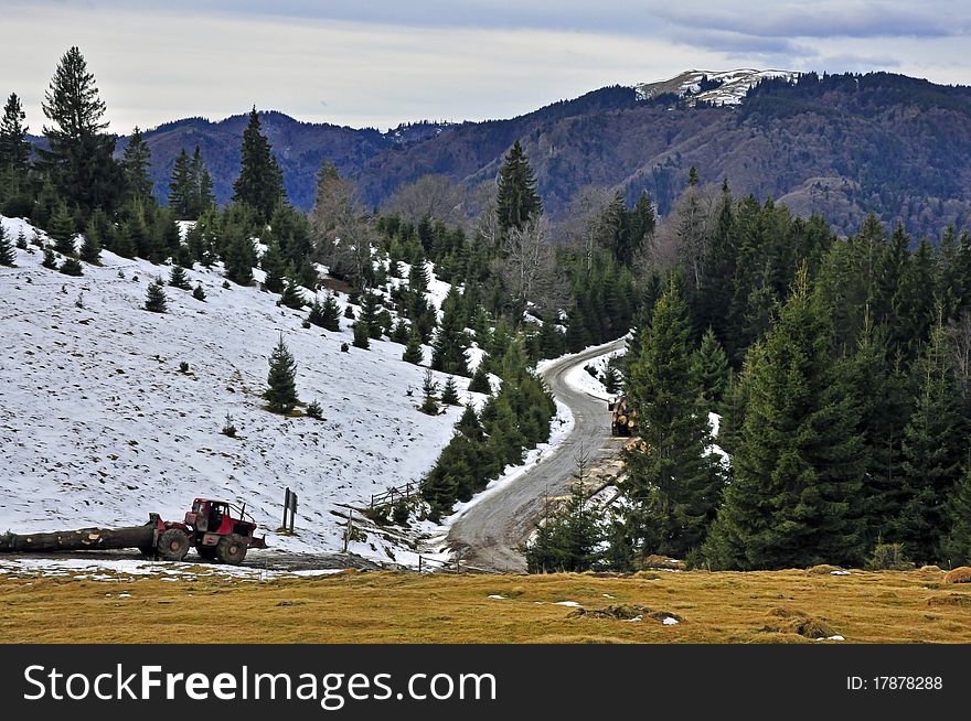 Working tractor in the forest mountains in winter time