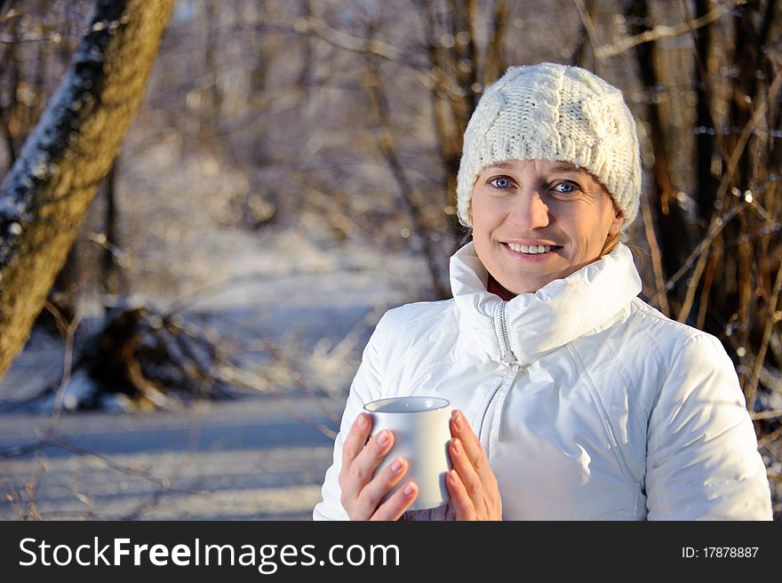 Woman in white, with a mug in his hands in a winter forest. Woman in white, with a mug in his hands in a winter forest.