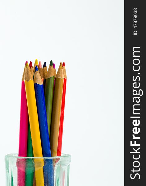 Colored pencils standing in an antique glass jar against a white background