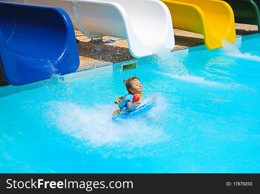 Little girl falls into the pool with water slides. Summer vacation