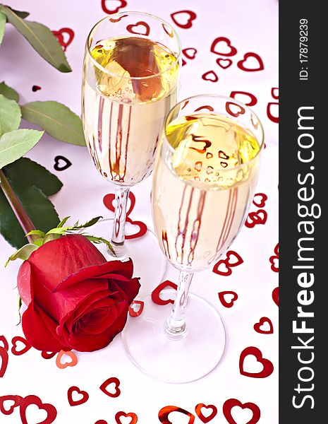 Beautifull red rose with two glasses of champagne on the pink surface with red hearts. Beautifull red rose with two glasses of champagne on the pink surface with red hearts.