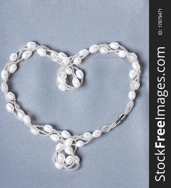 Heart-shaped string with pearls on a gray cloth. Heart-shaped string with pearls on a gray cloth