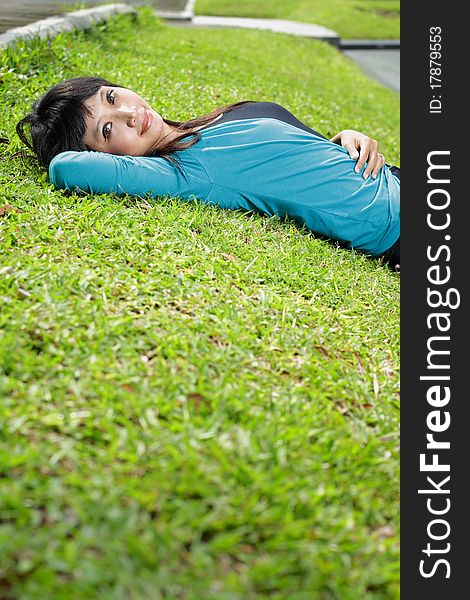 Young beautiful girl smiling and lying down on grass