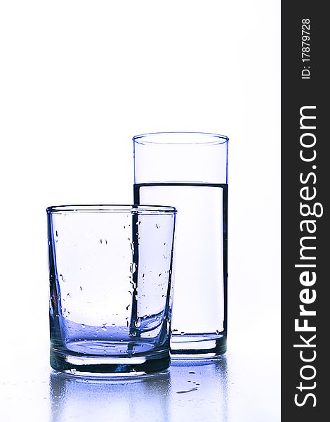 Empty glass before full glass of fresh water.