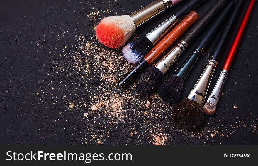 Set of different makeup brushes, makeup tools, textured dark background. Powder and eye shadow, copy space and Shine