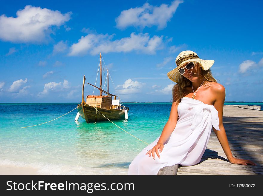 A young woman sits on a pier. A young woman sits on a pier