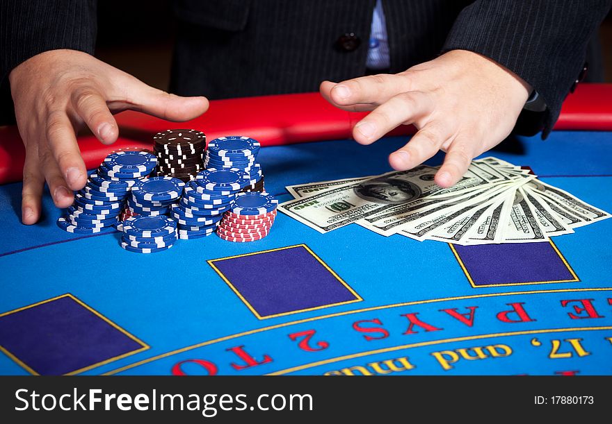 Close up of men's hand with chips, cards and one hundred dollars banknotes on poker table. Close up of men's hand with chips, cards and one hundred dollars banknotes on poker table