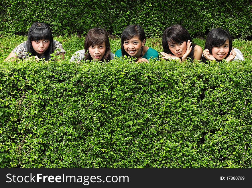 Girl friends group hiding behind the tree