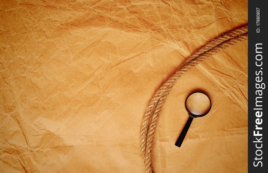 Magnifying glass and rope on old paper